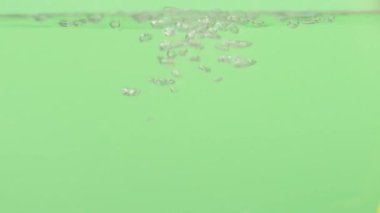 Sudaki hava kabarcıkları yeşil bir zeminde yukarı doğru yükselir. Yüksek kaliteli FullHD görüntüler