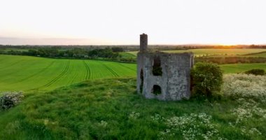 Havadan. Dairesel. Eski bir tapınağın kalıntıları bir tepenin üzerinde duruyor. Çiftçi tarlaları. Gün batımı. Kilkenny ülkesi. Yüksek kalite 4k görüntü