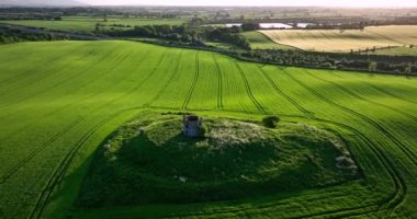 Havadan. Dairesel. Eski bir tapınağın kalıntıları bir tepenin üzerinde duruyor. Çiftçi tarlaları. Gün batımı. Kilkenny ülkesi. Yüksek kalite 4k görüntü