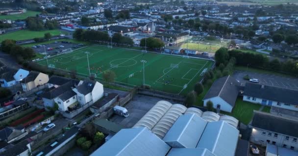エアリアル サーキュラー サッカー場でのトレーニング アイルランドのキルケニーのサッカー場の夜景 選手は夜にサッカーやトレーニングをする グリーンスタジアム 高品質の4K映像 — ストック動画