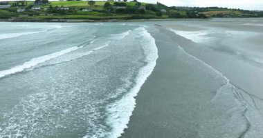Havadan. Resimli plajın oradaki sahil şeridi. Mavi suları ve beyaz dalgaları olan resimli bir sahil şeridi. Inchydoney Sahili. Clonakilty, County Cork, İrlanda. Ağır çekim. Yüksek kalite 4k görüntü