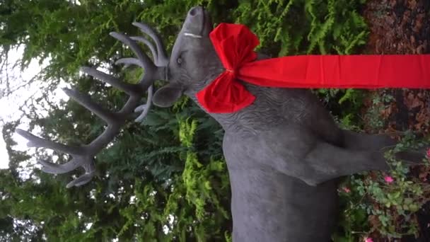 緑の火の木の背景に黒い弓で装飾されたアントラーを持つ鹿の像 クリスマスの装飾的なトナカイの装飾 クリスマスシンボル メリークリスマス 高品質の4K映像 — ストック動画
