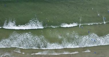 Mavi okyanus ve kumsalda köpüren ve ezilen büyük dalgaların olduğu Atlantik sahilinin en üst manzarası. Sörfçülerin sörf tahtasında dalgaları kontrol ettiği sarı altın kum. Liscannor Bay. yüksek kalite 4K görüntü.