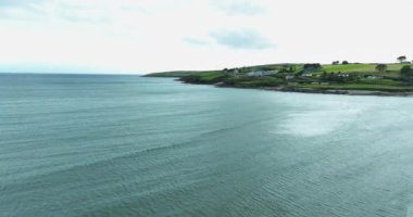 Havadan. Geniş kumsal. Okyanusun mavi dalgaları. Mavi okyanus suyu denizden esen güçlü rüzgar. Sahilin kenarındaki güzel beyaz evler. Clonakilty, County Cork, İrlanda. Yüksek kalite 4k görüntü