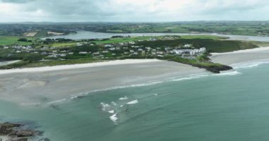 Havadan. Sahilin kenarındaki güzel beyaz evler. Mavi okyanus suyu denizden esen güçlü rüzgar. Inchydoney Plajı 4K Hava Görüntüleri, Clonakilty, County Cork, İrlanda. Vahşi Atlantik usulü. 4k görüntü