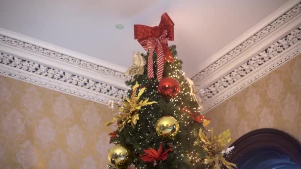 上に赤いバンティングが付いている抵抗力のないクリスマスツリー おとぎ話の家にあるクリスマスツリー ヴィンテージインテリア クリスマスツリー カントリーの古い家の豪華なインテリアのクリスマスツリー — ストック動画