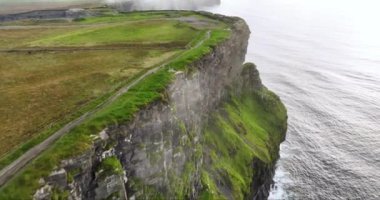Havadan. Moher 'in iskeletlerine döküldü, beyaz bulutlarla örtüldü. Yoğun siste gizlenmiş kayalıklar. Moher Kayalıkları 'nın üzerinden bulutların üzerinde uçuyor. Siste gizlenmiş kayalar. Beyaz dalgalar kayalara çarpıyor.