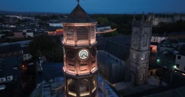 Kilkenny antik şehrinin arka planına karşı saat kulesi. Şehir merkezinde gün batımında eski bir saat. Tower Gothic Style Close View. Tholsel. St. Marys Katedrali. Yüksek kalite 4k