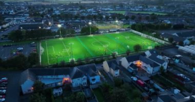 Havadan. Futbol sahasındaki projektörler açık. Açık stadyumun üzerinde büyük ışıklar yanıyor. Şehir merkezinde bir eğitim stadyumu. Kilkenny, İrlanda. Yüksek kalite 4k görüntü