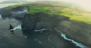 İrlanda 'nın batı kıyısındaki Moher' in güzel uçurumlarının hava manzarası. OBriens Kulesi alçak bulutlardan görülebilir. Etkileyici deniz yığınları. County Clare 'de. İrlanda. Yüksek kalite 4k görüntü