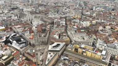 Merkezdeki Gotik katedralin önündeki Piazza Duomo 'nun hava manzarası. Gün boyunca galeri ve çatıların insansız hava aracı görüntüsü. Şehrin üzerinde uçuş. Şehirdeki turistler. Milan mı? Yüksek kalite 4k