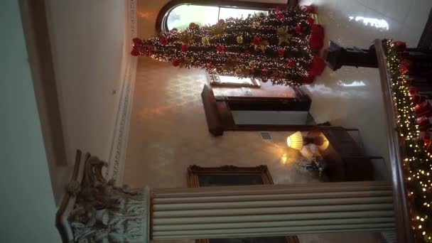垂直に おとぎ話の家にある 魅力的なクリスマスツリー 国の古い家の豪華なインテリアのクリスマスツリー ガーランドで飾られた大きな階段 アイルランド スローモーション 高品質で — ストック動画