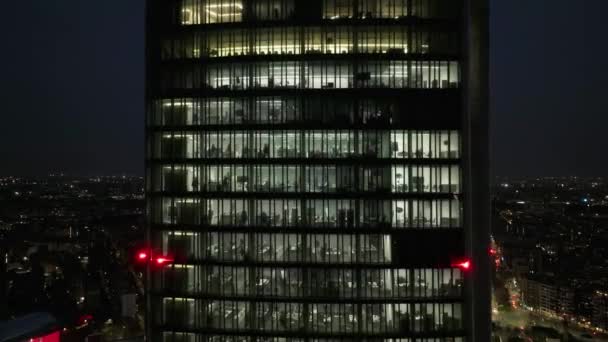 客室数が多いオフィスビジネスセンターは 夜に黄色い窓で輝いています 人々はオフィスセンターで夜に働きます ドローンは夕暮れのビジネススクーパーの窓に近づきます ミラノ イタリア — ストック動画