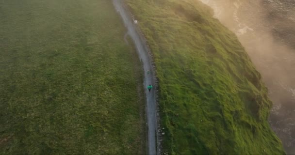 エアリアル 観光客はモハーの崖に沿って間違った道をたどる モハーの崖沿いの崖に沿って観光路の崖の上を歩いているマムと子供 美しい夕日 カントリークレア — ストック動画