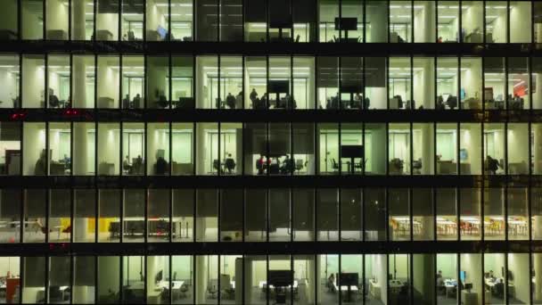 エアリアル 夜間の近代的なオフィスビルの大きな輝く窓は 窓の光の列に輝いています オープンスペースの作業場所 大企業は高層ビルのオフィスのためのスペースを借りる コーポレート コーポレート — ストック動画