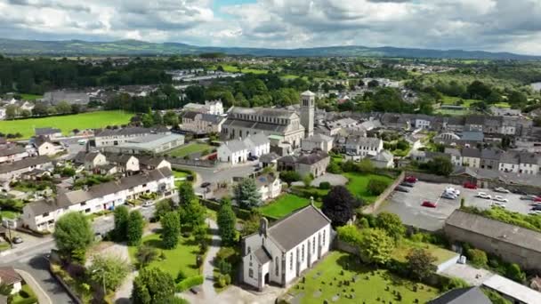 エアリアル スエアの古代アイルランドの都市キャリックのトップビュー セントニコラス カトリック教会の上空を飛ぶ 川の近くにある小さな町のパノラマ 曇りの日の上からの都市は 背景に対して — ストック動画