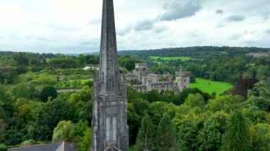 Yeşil tepelere ve ağaçlara karşı antik bir kale. Kaleyi çevreleyen yeşil ağaçlar. Akşam güneşi Castle. Waterford 'un verimli kırsalındaki Lismore Kalesi ve Knockmealdown Dağları