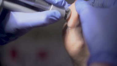 Podolojist ayağın topuğunu temizliyor. Podolojistlerin ofisinde öğütüyor. Sağlık, estetik, ayak ve tırnakların estetik ve güzelliği için pedikür ve pediatri tam tedavi