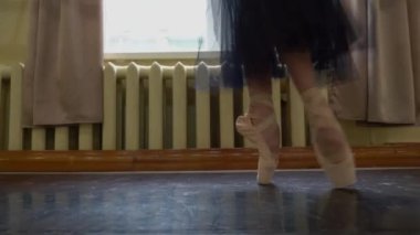 Karanlık sahnede ya da stüdyoda egzersiz yaparken balerin. Sivri uçlu ayakkabılı balerin yerde dans ediyor. Dansçı bacakları. Salonda bale eğitimi. Ayakları sivri uçlu kadınlar