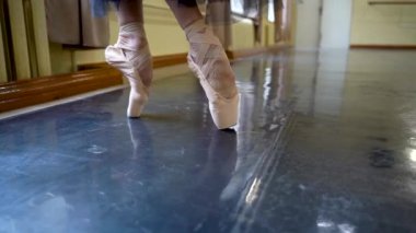 Yerde dans eden sivri uçlu ayakkabılı bir balerinin bacakları. Büyük salonda prova yaparken balerin ayakları. Sıkı çalışma ve dans eğitimi ve klasik koreografi sanatı. Yavaş Hareket