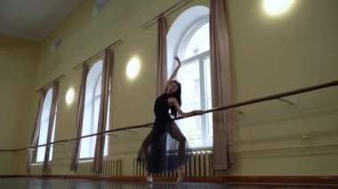 Beyaz etekli baş balerin dans sınıfında bale pozisyonu alıyor. Dans stüdyosundaki genç klasik dansçı kadın. Bale sınıfı eğitimi. Bale okulu konsepti. Yavaş