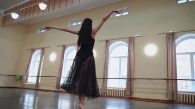 Sivri ayakkabılı baş balerin ve siyah bale elbisesi çok güzel dans figürleri gösteriyor. Büyük salonda klasik balerin unsurlarıyla dans eden zarif balerin. Dans stüdyosundaki klasik dansçı kadın.