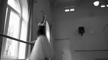 Beyaz etekli baş balerin dans sınıfında bale pozisyonu alıyor. Dans stüdyosundaki genç klasik dansçı kadın. Bale sınıfı eğitimi. Bale okulu konsepti. Yavaş