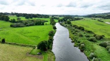 Karasu Nehri 'nin ve yeşil çimlerin üzerinde uçuyor. Gün batımında yaz manzarası. Yeşil bankası olan geniş bir nehir. Nehrin etrafındaki yeşil çayır ve yeşil ağaçlar. Gölün kıyısındaki köy hayatı. Sahilde...