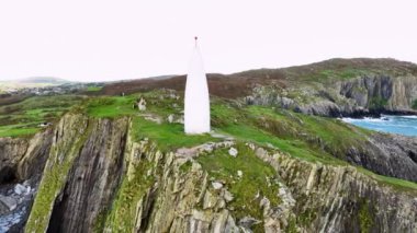 Baltimore Beacon 'ın ve Baltimore Coast Cork Ireland' ın kıyı uçurumlarının hava görüntüleri. Güzel bir yer. Kayalık bir sahil şeridinin ortasında beyaz bir deniz feneri. Günbatımında Baltimore Feneri