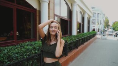 Kadın konuşuyor, cep telefonu konuşuyor, sokakta yürüyor. Teleksle konuşan ve saçını düzelten güzel bir kadın. Yürüyen bir kadın, çekici bir sırt çantalı, şehirde yürürken sohbet eden, güzel bir turist.