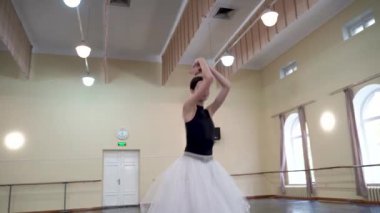 Profesyonel bir balerin büyük bir eğitim salonunda tek başına dans eder. Opera binasının eğitim salonunda bir balerin dans ediyor. Bir balerin, büyük bir bale salonunun ortasında tek başına dans eder.