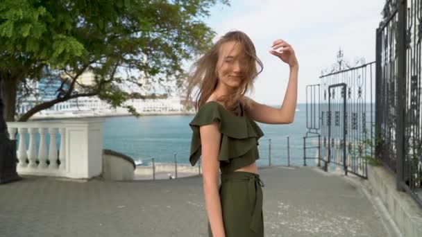 在美丽的欧洲长廊的背景下 快乐的女孩微笑着 夏日周末 优雅的女性游客站在长廊上 在人行道上摆出一副无忧无虑的样子 看着相机 — 图库视频影像