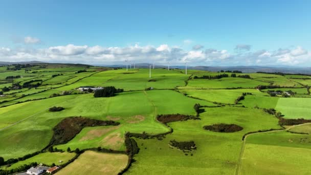 景色の緑の丘に再生可能エネルギーを生成する白い回転ウィンドミルブレードのシネマティックな空中ビュー 再生可能エネルギー 持続可能な開発環境に優しいコンセプト4K自然ショット — ストック動画