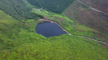 Dağların ortasında bir vaha var. Tonelagee Dağı 'ndan Lough Ouler' in hava görüntüsü. Yeşil tepelerin ortasındaki dağ gölü. Dağın tepesindeki dağ gölünün temiz suları.
