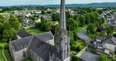 Havadan. Dairesel. Yeşil ağaçların arkasındaki güzel kilise. St. Carthages Katedrali Lismore, Waterford, İrlanda 'nın ortasında büyük bir katolik kilisesi. Lismore Kalesi ve Nakavt