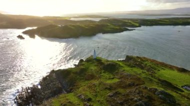 İrlanda, County Cork 'taki Baltimore Beacon' ın 4k hava görüntüleri. Güzel Atlantik kıyısında gün batımı. Gün batımında deniz feneri. Günbatımında okyanusun arka planında beyaz deniz feneri. Kayalık.