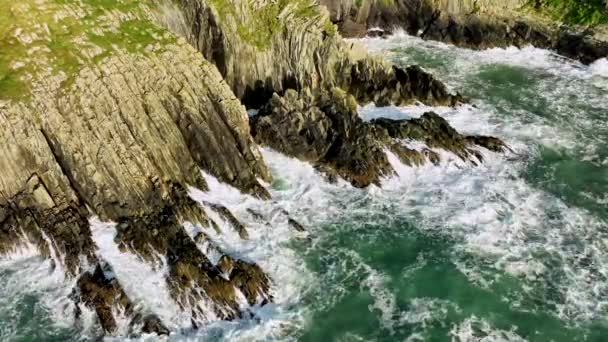風光明媚な岩の海岸の自然の背景 世界的に有名な海岸線の野生のシネマティックな空中観察 アウトドアの冒険と旅行 岩山の高い崖にオーシャンブルーの波がぶつかりました ワイルド — ストック動画