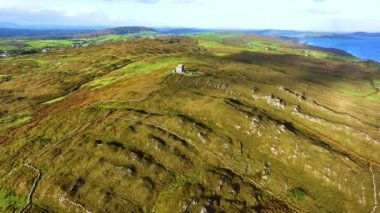 Baltimore 'da günbatımında antik bir kule. İspanya Kulesi. Yeşil tepelerin arka planına karşı inanılmaz manzaralar ve antik kalıntılar. Deniz kenarında gün doğumu. Doğanın sinematik hava manzarası dünyaca ünlü
