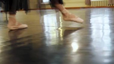 Sivri uçlu ayakkabılı balerin kameraya doğru yürüyor. Dansçılar bacaklarını kapatır. Balerin bacakları yakın. Sivri uçlu balerin ayakları. Salonda bale eğitimi. Yüksek kalite 4k görüntü