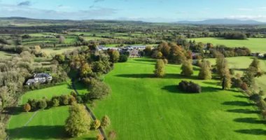 Yeşil çimlerin üzerinde bir malikane. Köy evi ya da köy evi. Yeşil çimlerin üzerinde şık bir ev. Doğanın arka planına karşı köy ikametgahı. İrlanda Kır Evi ve Kilkenny Bahçeleri yüzüğü