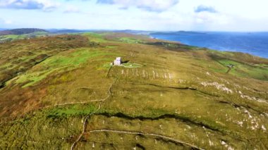 Baltimore 'da günbatımında antik bir kule. İspanya Kulesi. Yeşil tepelerin arka planına karşı inanılmaz manzaralar ve antik kalıntılar. Deniz kenarında gün doğumu. Doğanın sinematik hava manzarası dünyaca ünlü