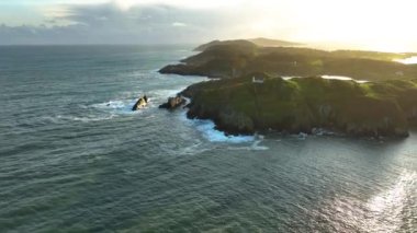 Baltimore Beacon, Güney Batı Cork 'ta gün batımında. Baltimore, County Cork 'ta kayalık bir sahil manzarasında pitoresk bir deniz feneri. Baltimore Beacon, beyaz boyalı taş kule girişte.