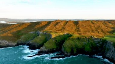 Baltimore 'daki antik kuleye ait hava görüntüleri. İspanya Kulesi. Yeşil tepelerin arka planına karşı inanılmaz manzaralar ve antik kalıntılar. Deniz kenarında gün doğumu. Doğanın sinematik hava görüntüsü