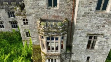 Eski bir kalenin pencereleri. Gün batımında yeşil ağaçlara sarılı, nehrin kıyısında pitoresk bir kale. Akşam güneşi Castle. Lismore Kalesi ve Knockmealdown Dağları yemyeşil kırsalda