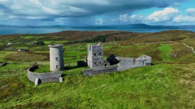 Havadan. Büyük bir adanın tepesinde antik bir deniz feneri. Yeşil bir ada ve İrlanda 'nın ortasındaki antik bir kalenin kalıntıları. Deniz manzarası ve yağmur bulutlarına karşı antik kalıntılar. Deniz feneri