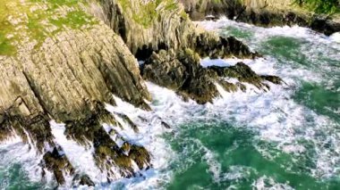 Hava 4k. Sahildeki kayalık doğa arka planı. İrlanda, County Cork 'ta Baltimore Beacon' ın saf doğasını geziyorum. Vahşi doğanın sinematik hava manzarası dünyaca ünlü kıyı şeridi. Açık hava macerası