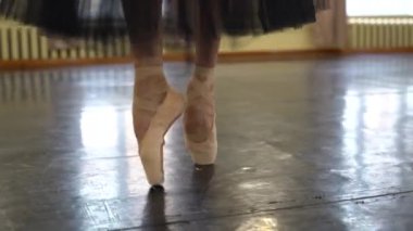 Sivri uçlu ayakkabılı balerin kameraya doğru yürüyor. Dansçılar bacaklarını kapatır. Balerin bacakları yakın. Sivri uçlu balerin ayakları. Salonda bale eğitimi. Yüksek kalite 4k görüntü