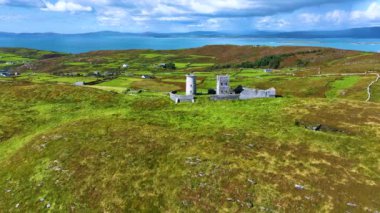 Havadan. Büyük bir adanın tepesinde antik bir deniz feneri. Atlantik Okyanusu 'nun ortasındaki yeşil bir adada antik bir deniz feneri. Yeşilin ortasındaki antik bir kalenin kalıntıları.