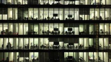 Geceleri modern ofis binalarında büyük parlayan pencereler, pencereler ışık saçıyor. Açık alan çalışma alanları. Büyük şirketler gökdelenlerdeki ofisler için yer kiralarlar. İş adamları ve ofis