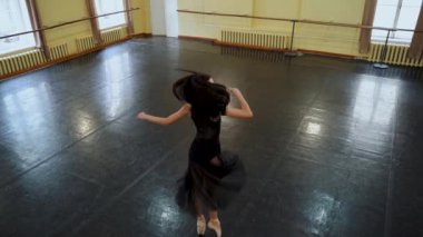 Baş balerin, bale salonunun ortasında dairesel hareketler sergiliyor. Güzel dans figürleri gösteriyor. Zarif balerin büyük bir salonda klasik balerin unsurlarıyla dans eder. Dans stüdyosu